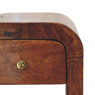 Close detail of the chestnut nightstand's curved top edge and the small round brass drawer handle.
