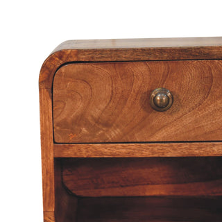 Close-up detail of the honey wood grain, rounded corner, and antique brass drawer knob.