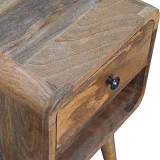 Close detail of the oak-ish wood grain on the top surface and the rounded front corner of the bedside table.