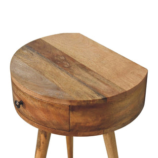 Close detail of the bedside table's curved top surface, highlighting the rich wood grain and small bronze drawer pull.