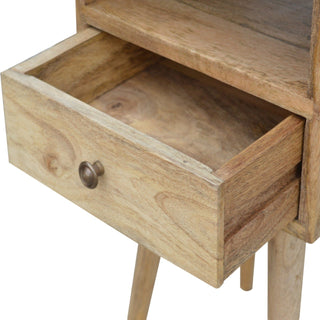 Close-up showing the wooden drawer of the bedside table pulled open, with the antique brass knob visible.