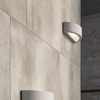 Close-up of two concrete wall lights mounted vertically on a textured concrete-effect tiled wall.
