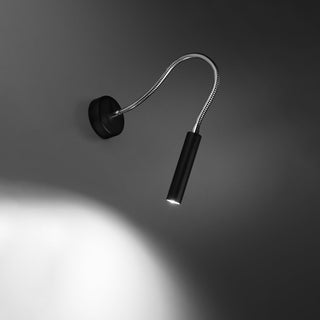 Black wall light fixture with flexible silver arm casting a bright spotlight beam onto the dark wall below.