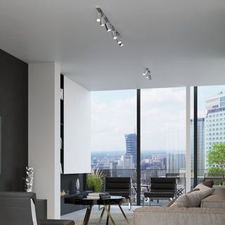 Modern open plan living space with large windows and chrome spotlights installed on the ceiling.