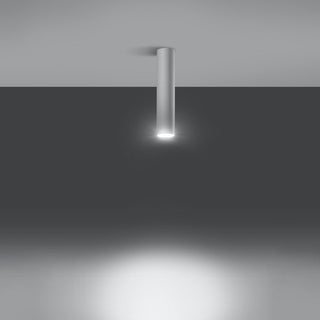 White cylindrical ceiling light fixture switched on, casting a bright downward spotlight beam onto a dark wall.
