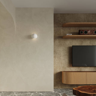 White globe wall light illuminating a textured beige wall next to a wooden media unit.