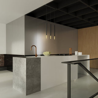 Styled shot showing the three-light pendant fixture installed over a contemporary kitchen island.