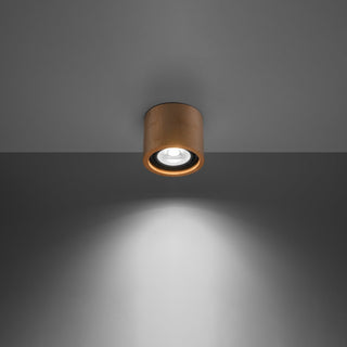 Cylindrical natural wood ceiling light fixture illuminated, showing the focused downward light beam.