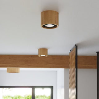 Multiple natural wood cylindrical lights installed on a white ceiling and a large wooden beam.