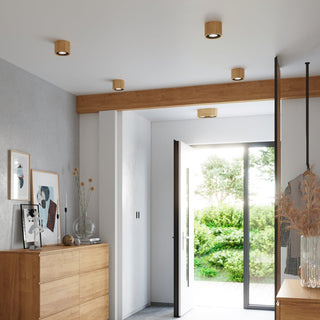 Multiple natural wood ceiling lights illuminating a modern hallway with wooden furniture.