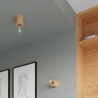 Two natural wood lamp bases mounted on grey walls and ceiling, complementing the adjacent oak storage unit.
