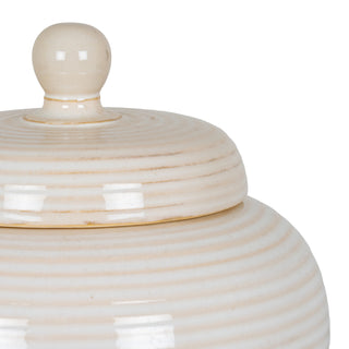 Tight detail of the cream ceramic jar lid and body, showing the ribbed glaze and spherical finial.