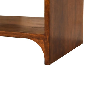 Close-up detail of the dark wood bedside cabinet base, showing the curved foot cut-out and open storage shelf joint.