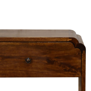 Close-up detail of the dark wood finish, curved top edge, and metal drawer knob on the bedside cabinet.