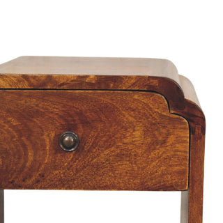 Detail showing the rich chestnut grain, curved top, and antique brass drawer knob.