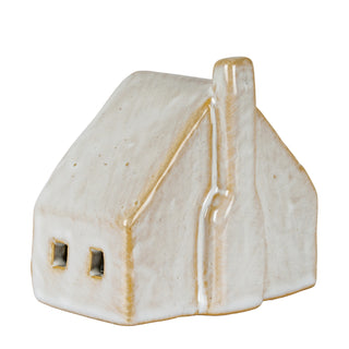 Side profile of the ceramic cottage highlighting the thick, rustic beige and white glaze and chimney.
