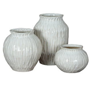 Three white ceramic vases of varying sizes and shapes, all featuring the same irregular vertical texture.