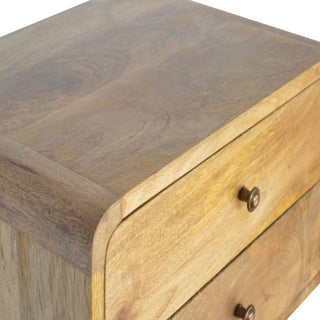 Tight close-up showing the wooden top surface, rounded side edge, and brass knob on the top bedside drawer.
