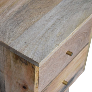 Close-up showing the varied natural wood grain and colour of the bedside table top and drawer fronts.