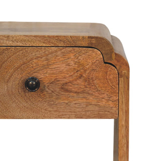 Close-up of oak-ish wood grain, dark drawer knob, and curved corner detail.