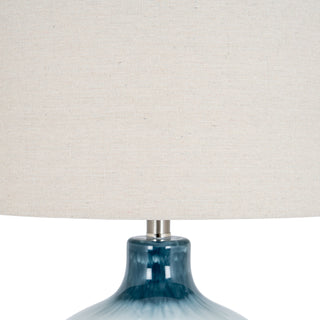 Detail shot showing the coarse texture of the linen shade above the glossy blue ceramic lamp base.