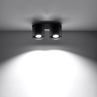 Black ceiling light demonstrating two bright pools of illumination cast onto the wall.