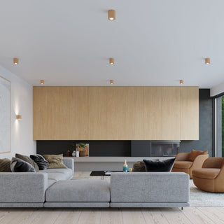 Multiple cylindrical wood ceiling lights illuminating a contemporary living room with a large grey sofa and wood panelled wall.