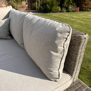 Close up showing the texture of the light grey cushions and the woven rattan side panel.