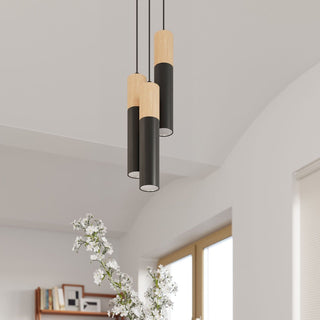 Three black and wood pendants hanging at varying heights in a bright room with white flowers in the foreground.