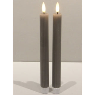 Front view of two grey ribbed flameless taper candles with illuminated tips.