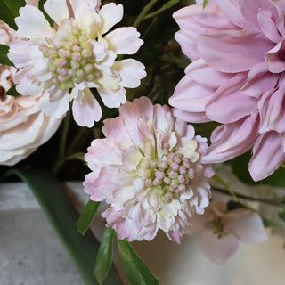Close-up of two pale pink artificial scabious blooms arranged with other faux flowers.