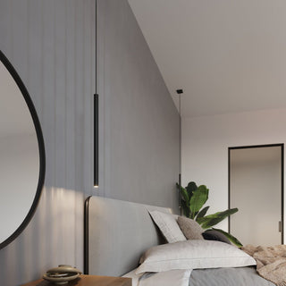 Modern bedroom setting with a black cylindrical pendant light suspended next to a large round mirror and upholstered headboard.