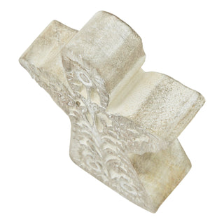 Angled close-up showing the rough texture and deeply carved detail on the top edge of the wooden angel.