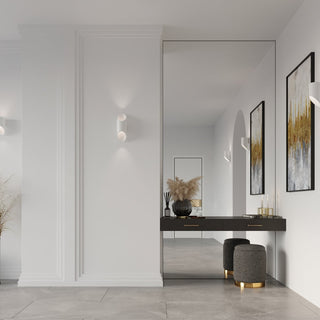 White cylindrical wall lamp installed in a modern hallway with decorative panelling and a large mirror.