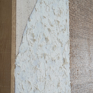 Close-up showing the junction of the wooden frame, textured paint, and coarse brown textile elements.