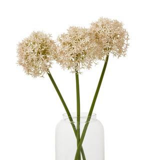 Three artificial pink allium stems displayed in a clear glass vase against a white background.