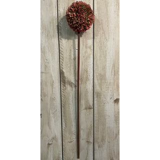 Full length artificial pink allium against vertical distressed white wood panelling.