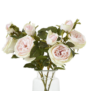Arrangement of multiple artificial pale pink rose stems and buds displayed in a clear glass vase.