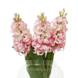 Three artificial pink hyacinth stems displayed together in a clear glass vase.