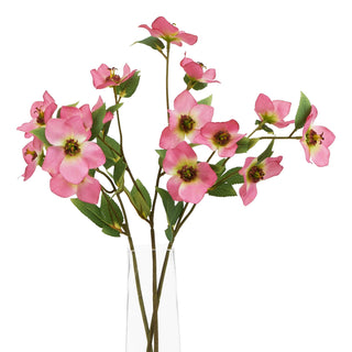 Artificial pink hellebore stems displayed as a bouquet in a transparent glass vase.