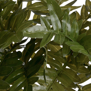 Extreme close-up of artificial green leaves, showing detailed texture and segmented structure against a white background.