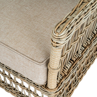 Close detail of the woven rattan frame and the textured beige outdoor seat cushion.