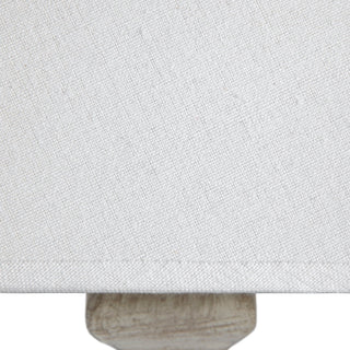 Detail shot showing the woven texture of the white linen shade resting on the whitewashed wooden base.