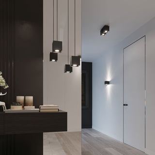Quad black ceiling light installed in a modern hallway alongside matching wall and pendant lamps.