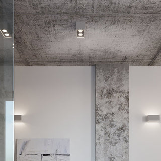Grey ceiling lamp and two matching wall lights in a modern room with a textured concrete ceiling and white walls.