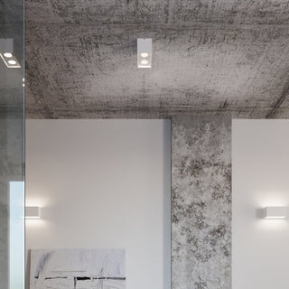 Concrete ceiling with white quad lamp, matching rectangular wall lights, and a vertical glass partition.