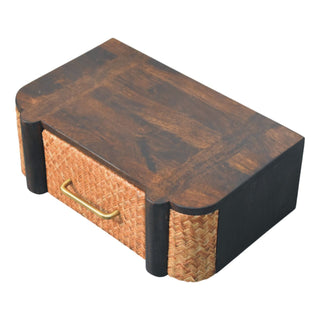 High-angle view of the dark wood wall drawer, showing the top surface grain, rattan front, and brass handle.