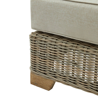 Detail of the beige cushion resting on the chunky grey rattan weave and small wooden foot.