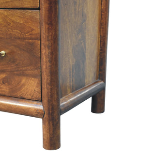 Close-up showing the rounded wooden frame, base rail, and short, thick legs of the chest.