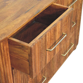 Detail of the amber oak chest showing the open top drawer and brass handles on the drawers below.